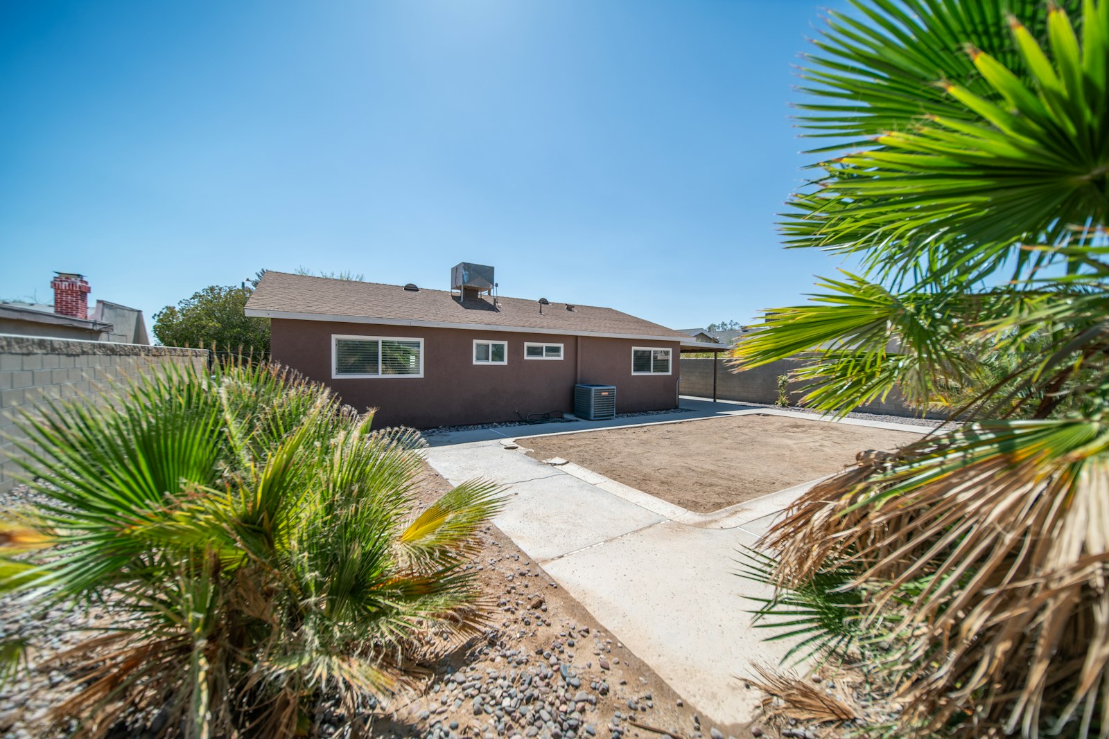 Two-story Surprise home with skirted Mexican fan palm and trimmed front lawn after a weekly visit.